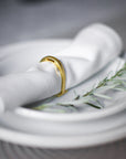 Gold napkin rings holding white napkins.