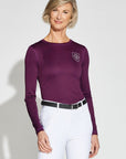 Woman wearing a long-sleeve purple riding shirt with white riding leggings.