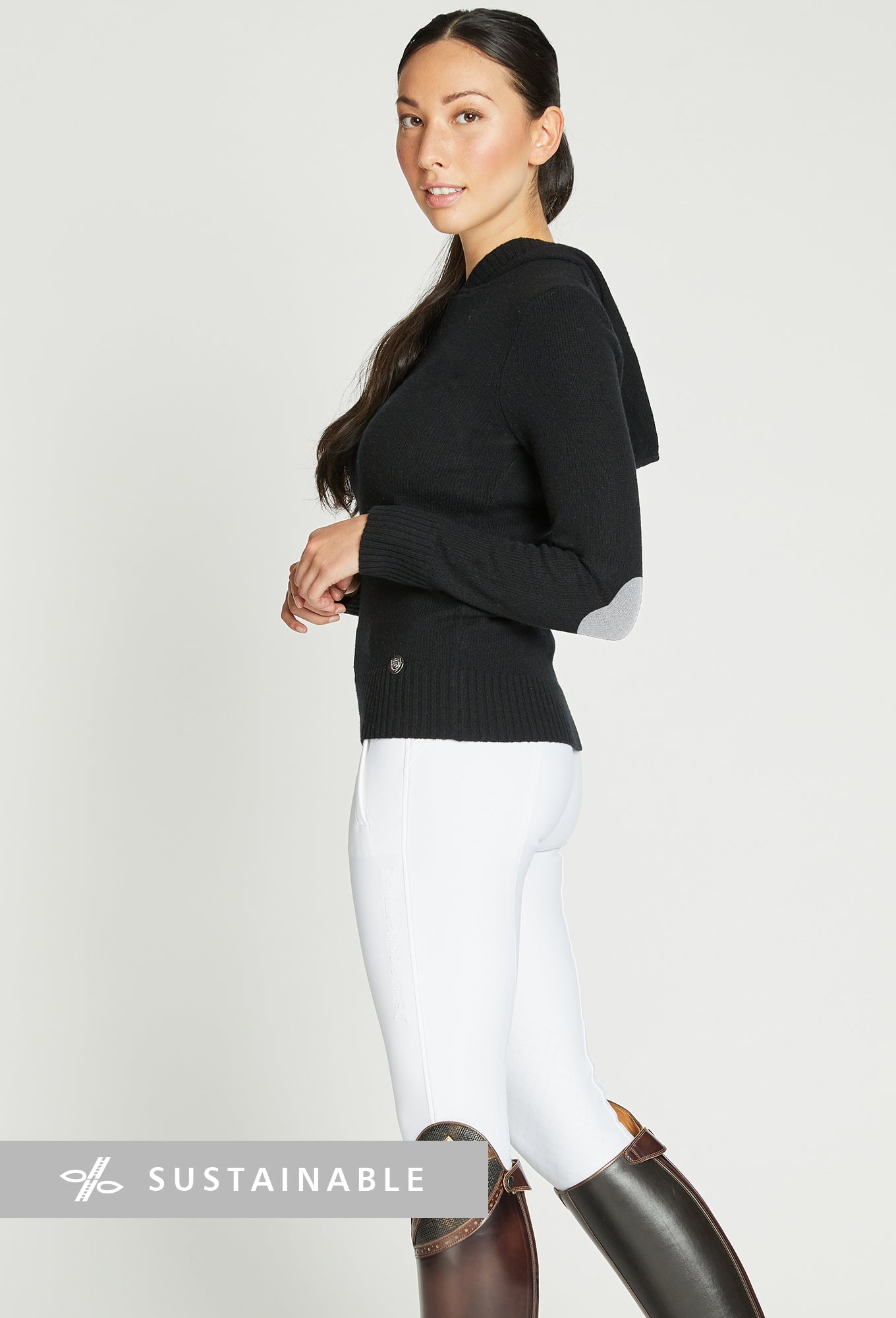 Woman wearing a black knit sweater and white riding leggings.