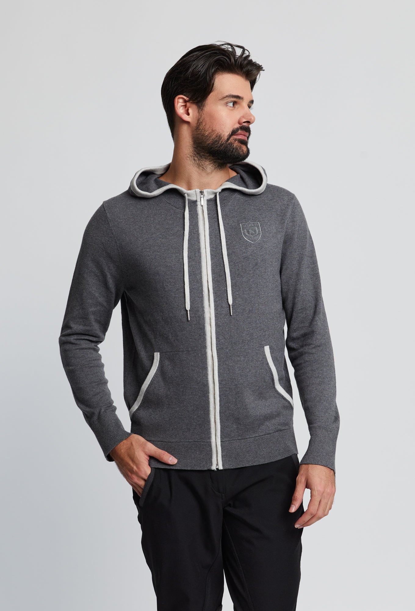 Men wearing grey hooded sweater with white trim on hood and pockets.