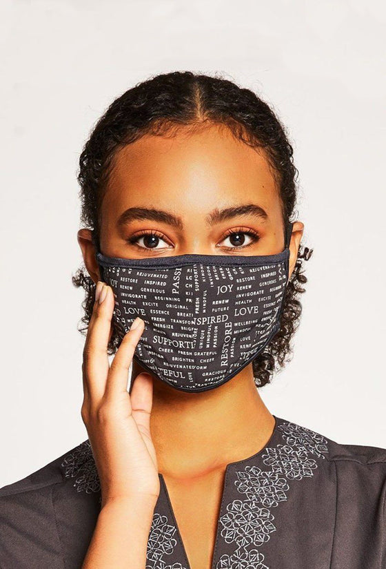 Woman wearing a black face mask with a design featuring multiple inspiring words in white font.