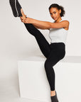 Woman points her right leg in the air while wearing black compression fit riding leggings.